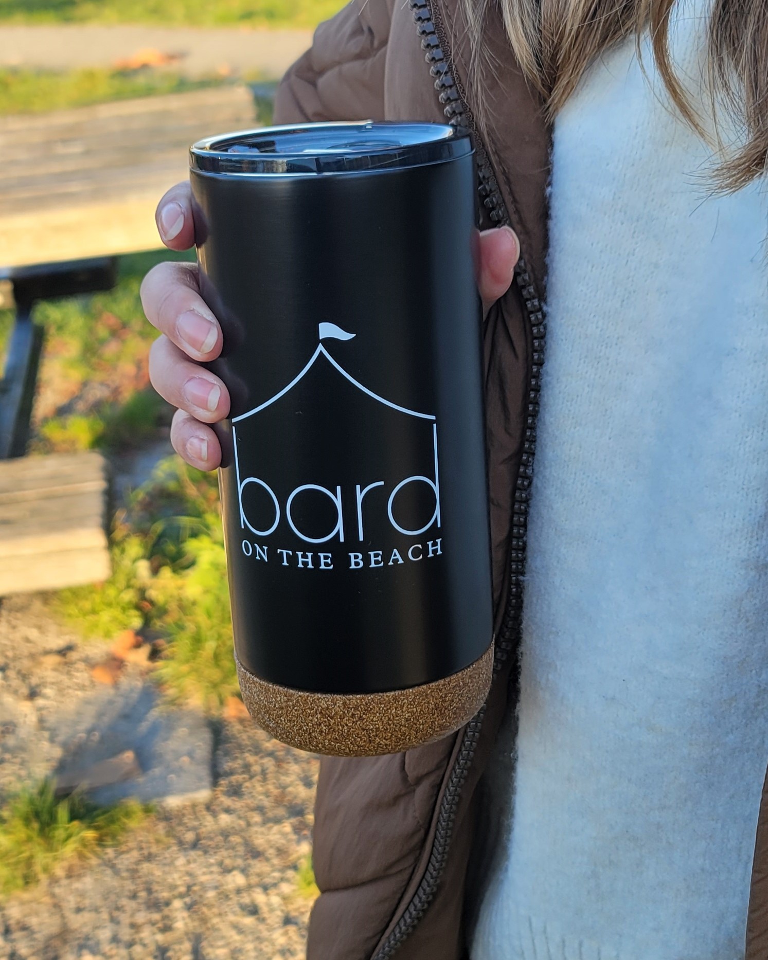 Person holding black Bard on the Beach Tumbler outside in the sunshine