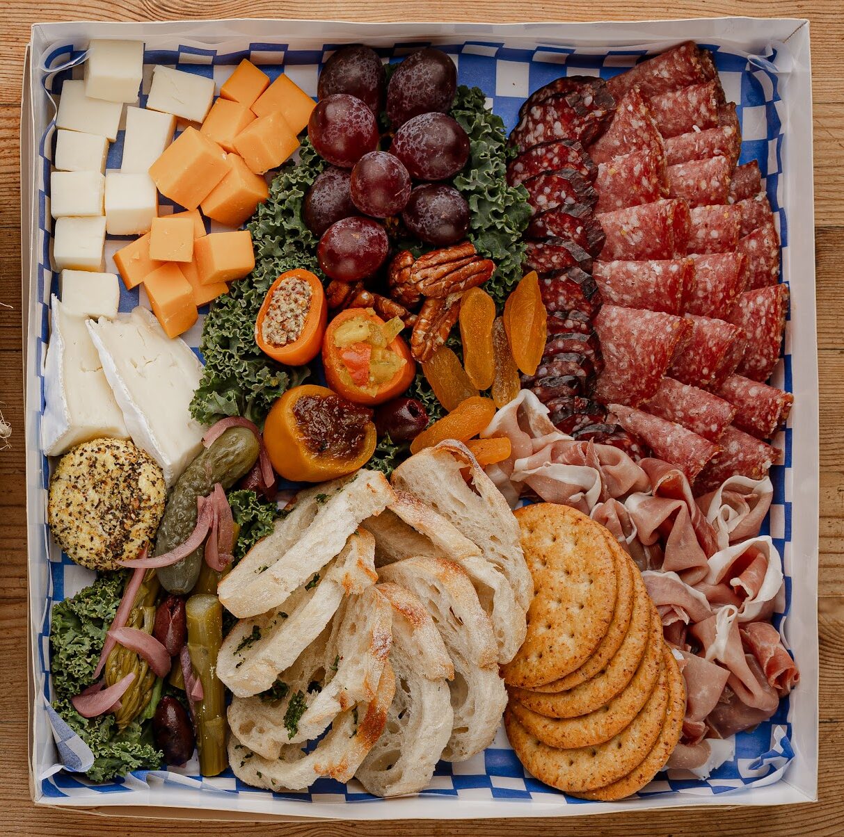 charcuterie box with bread, crackers, cheese, meats, and produce