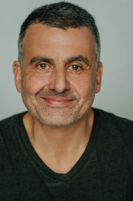 Marcus Youssef, in a black t-shirt, smiles at the camera.