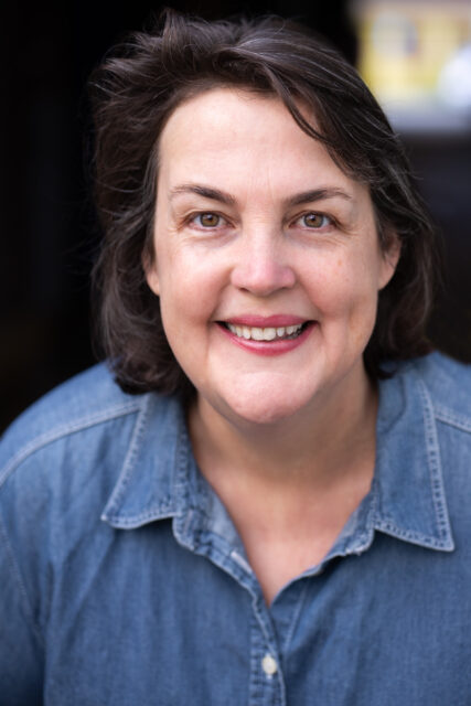 A headshot of Nicky Anderton, wearing a blue chambray button-up shirt.