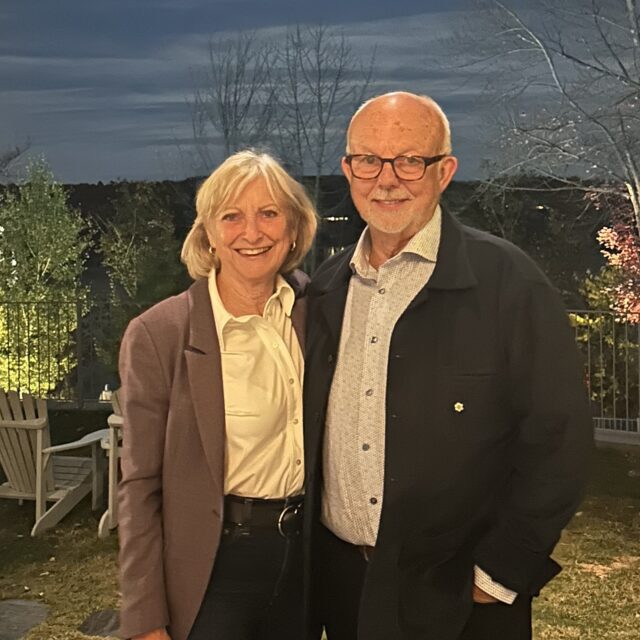 Christopher Gaze and his wife Jennifer posing for a photo in front of the water.